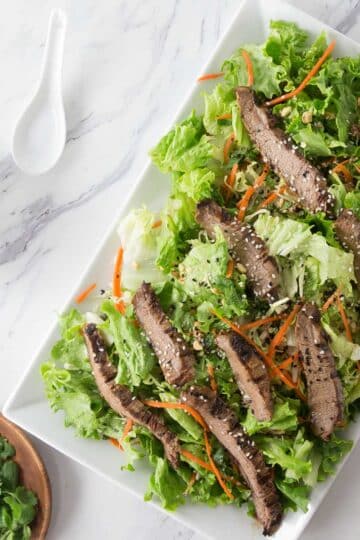 A white plate with Thai beef salad.