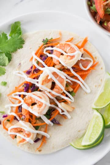 An overhead photo of shrimp tacos on a white plate.