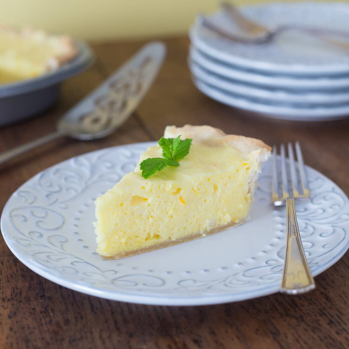 A photo of orange and lemon chiffon pie on a white plate with a fork.